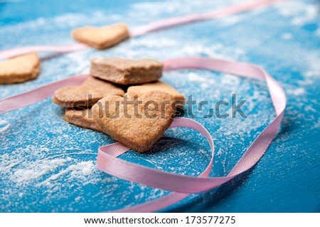 Cookie-hearts on a blue background with a pink ribbon powdered with a sugar