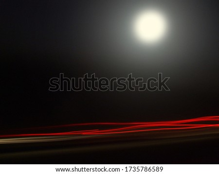 Abstract long exposure photograph of cars beneath the moon