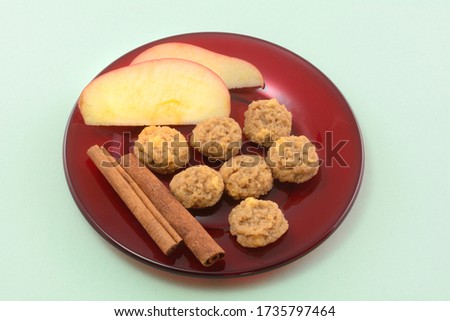 Cinnamon apple mini cookies with apple slices and cinnamon sticks on red glass dessert plate on green background