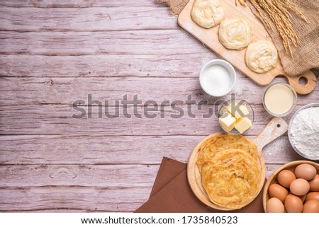 Roti pictures of Indian and Muslim food. And various ingredients such as eggs, flour, sugar, butter, sweet milk, and cooking tools are all on the old wooden table, with copy space.