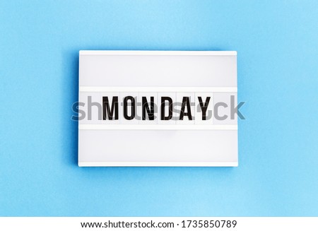 Text "monday" on lightbox for holiday - Thank God It's Monday. Start of working week concept. Top view on blue background.