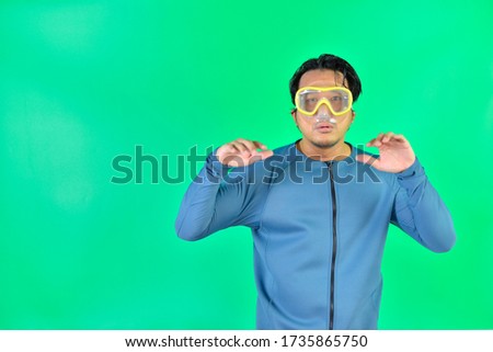Asian man wearing diving suit and snorkel mask on over green screen background.