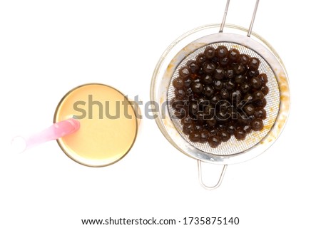 Flatlay selective focus picture of pearl milk tea in glass with tapioca ball or bubble tea insight.