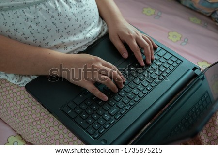Asian Chinese Pregnant woman in her bed working on computer 