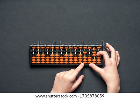 Child counting on soroban abacus. Black background with copy space. Concept education, school arithmetic, calculating thinking Royalty-Free Stock Photo #1735878059
