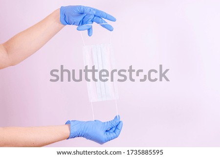 blue-gloved hand holds a medical mask. covit-19 coronavirus pandemic