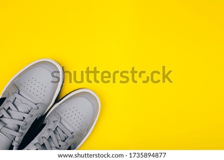 Stylish gray sneakers on a yellow background, healthy lifestyle, jogging, sports shoe store