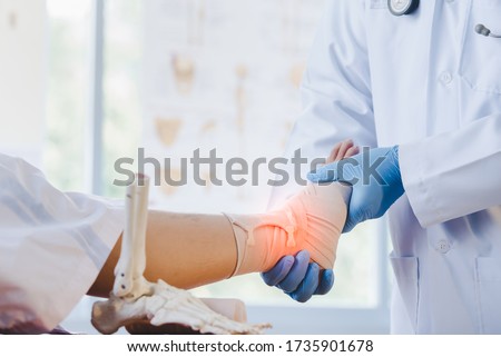 Close-up of pictures of a male orthopedic doctor or orthopedic doctor Wear a medical mask and medical gloves. Going to analyze the cause of ankle bone degeneration In his office at the hospital Royalty-Free Stock Photo #1735901678