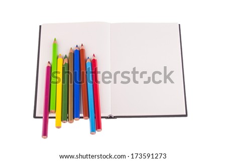 Color pencils placed on notebook, isolated on white background, picture with the place for text.