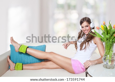 Beautiful young woman listening to music while doing leg exercis