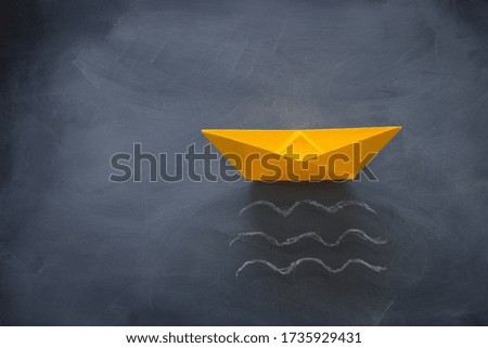 banner of single paper boat over blackboard background