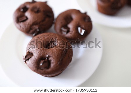 Close-up of delicious chocolate muffins with crispy top served on white plate. Homemade tasty cupcakes with cocoa stuffing. Yummy dessert and sweets concept