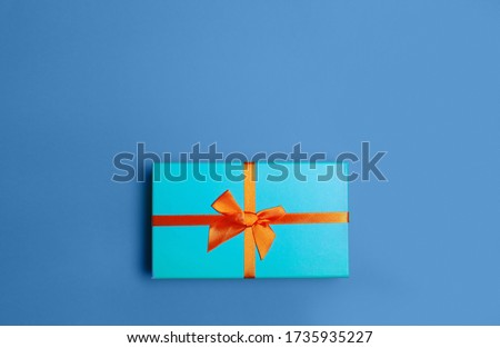 Green Christmas gift box on blue classic color background flat lay top view