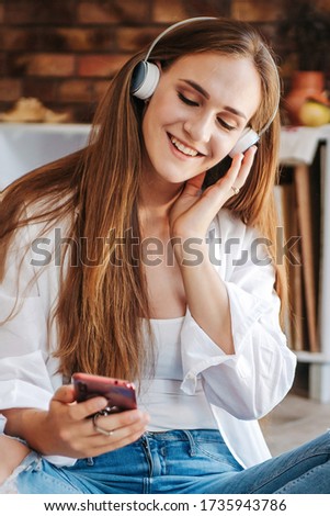 Artistic happy woman in headphones listening music, enjoying smartphone sound