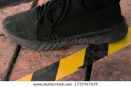 Close up on foot next to marking on the ground and signage for physical or social distancing to fight against the transmission of the covid-19 virus