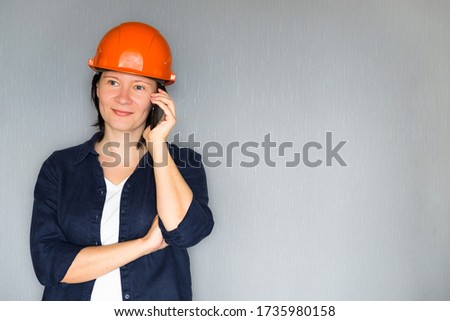 Beautiful woman architect talking on mobile phone against grey background. Successful happy beautiful lady smiling with copy space.
