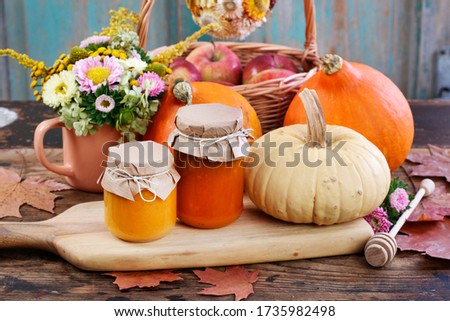 Glass jars with pumpkin jam and honey. Fresh vegetables on the table. 
