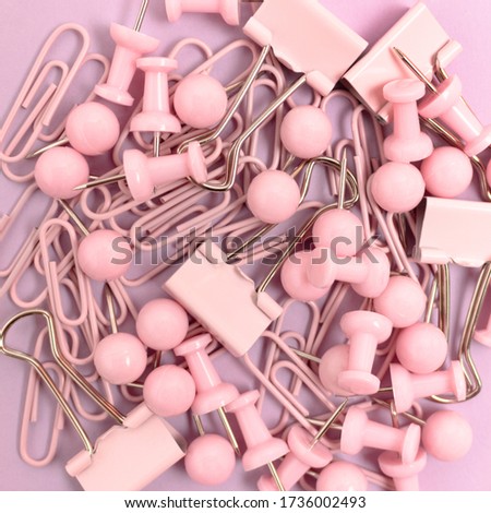 Texture made of paper clips and push pins on a pink pastel background. Monochromatic concept.