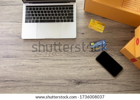 Top-down photo with copy space of laptop computer with smart phone, full of boxes and mock up credit cards for shopping online  store and electronic commerce for the digital life style.