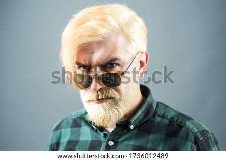 Head and shoulders portrait of a bearded middle-aged man looking thoughtfully at the camera over studio background with copy space