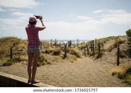 A view of a person taking a picture of the sky from the shore by the sea