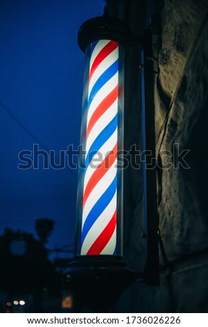 Barber pool/pole, the symbol of a barbershop. Stripes red, blue,white. The top and bottom of a metal. Barbershop pool on wall, evening barbershop. Barber’s Pole.