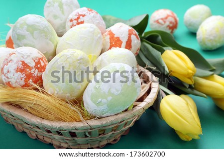 Easter speckled eggs and tulips in a basket on green background