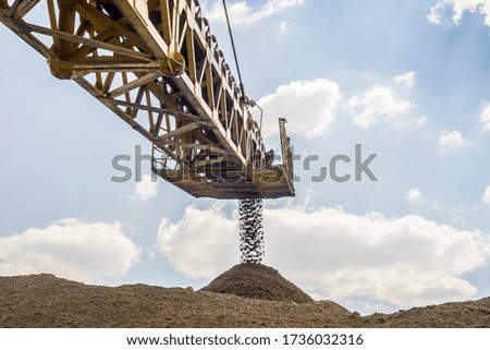 Crane unloading a large quantity of sand at construction site