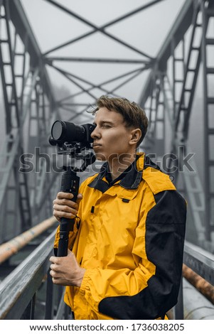 Young man videographer exploring foggy urban landscapes.