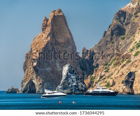 Yachts in the Sea on a background of rocky shores. Sea landscape with yachts and rocky coastline. Copy space. The concept of calmness, silence and unity with nature.