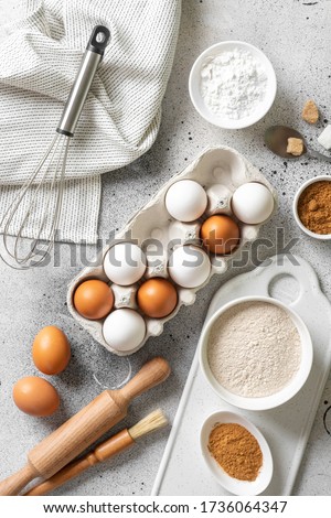 Ingredients for baking on a culinary background. Eggs, flour, cinnamon, sugar, soda on the kitchen table. Concept of preparation for baking. Top view with space for text Royalty-Free Stock Photo #1736064347