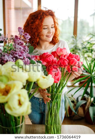 Florist at work: pretty young redhair woman making fashion modern bouquet of different flowers