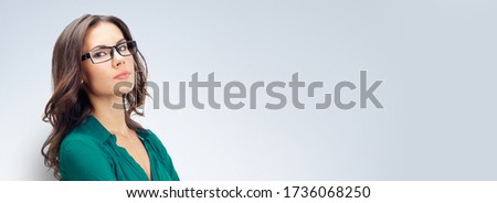 Portrait of serious young business woman in green confident clothing and glasses, over grey background. Copy space empty place for some ad text or imaginary. Hispanic Latino Caucasian female model.
