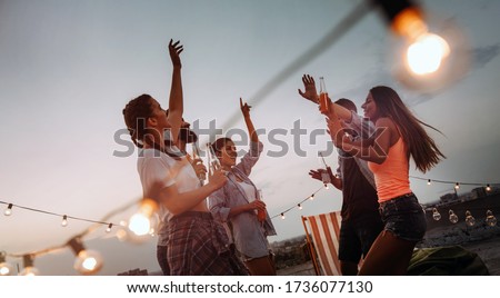 Carefree group of happy friends enjoying party on rooftop terrace Royalty-Free Stock Photo #1736077130