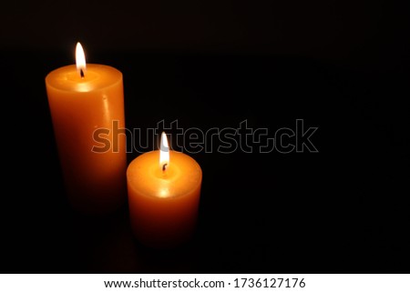 Close Up Of Candles Burning On Table Against Black Background