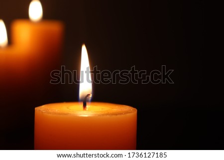 Close Up Of Candles Burning On Table Against Black Background