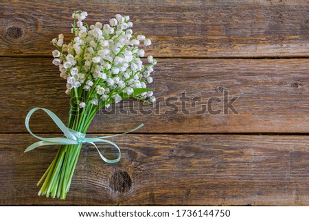 Beautiful bouquet of white lily of the valley flowers on a wooden table
