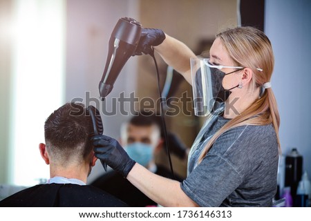 A hairdresser with security measures for Covid-19, blow-dry a man in a medicine mask, social distance, cutting hair with a medical mask, eye mask and rubber gloves in a beauty salon
 Royalty-Free Stock Photo #1736146313