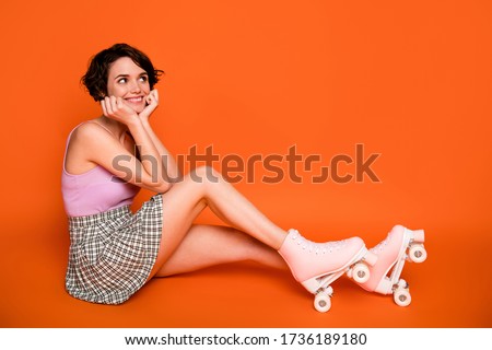 Full body profile side photo of positive cheerful girl sit floor look copyspace think thoughts riding skates rink wear pink singlet plaid clothes isolated over bright shine color background