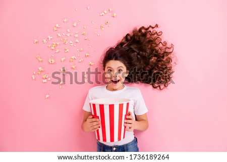 Top view above high angle flat lay flatlay lie concept portrait of her she nice lovely funny cheerful wavy-haired girl eating corn having fun watching movie isolated on pink pastel color background