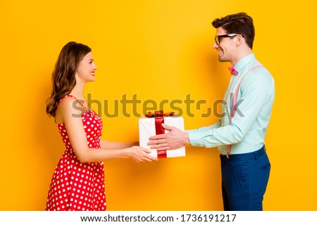 Profile photo of pretty lady handsome guy couple boyfriend giving girlfriend big gift box 8 march present wear red dotted dress shirt bowtie pants isolated yellow bright color background