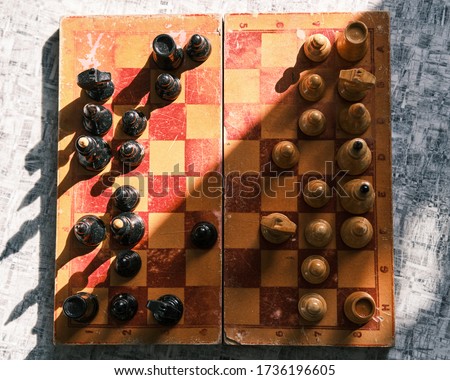 old chess and black and white pieces under hard light with a top view