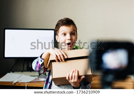 child blogger takes pictures of himself on a camera, smiling, unpacking a blog, video recording at home for a blog