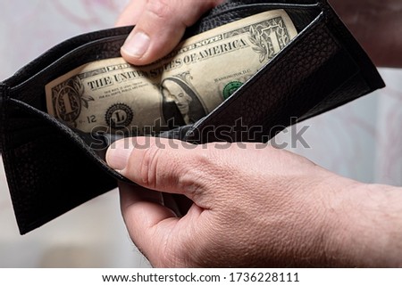Black leather wallet with one dollar in the hands of a man. Bankruptcy and Poverty Concept