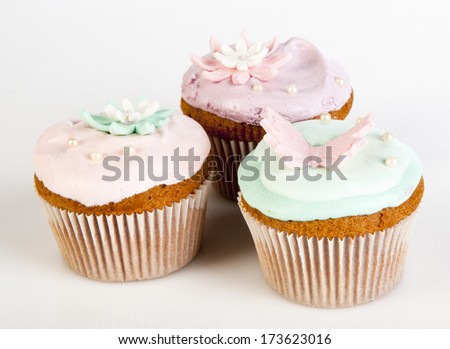 Three cupcakes with colorful sweet lilies and butterfly isolated on white background