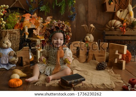 A little cute baby with lace dress and flower bonnet in front of the autumn and pumpkin background. 