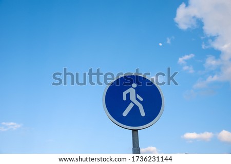 Round road sign with a silhouette of a person indicating that there is a pedestrian zone in front. Warning, car is prohibited. Traffic signs on a background of blue sky

