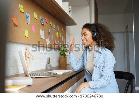 African teen girl student wear headphones waving hand video conference calling online on laptop computer at home office. Elearning zoom app video call, distance videoconference class with teacher. Royalty-Free Stock Photo #1736246780