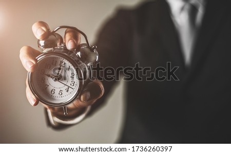 Businessman holding retro alarm clock. time management and time is money concept.
