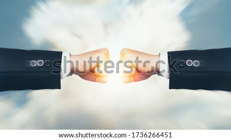 Fight, Interruption and coping with economic conflicts, competition with business competitors during the covid-19. Two fists hitting with sunlight effect on sky background. Concept of struggle.